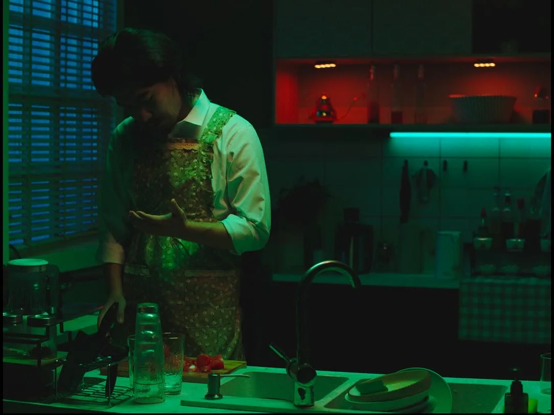 A man isolated within the green-lit kitchen