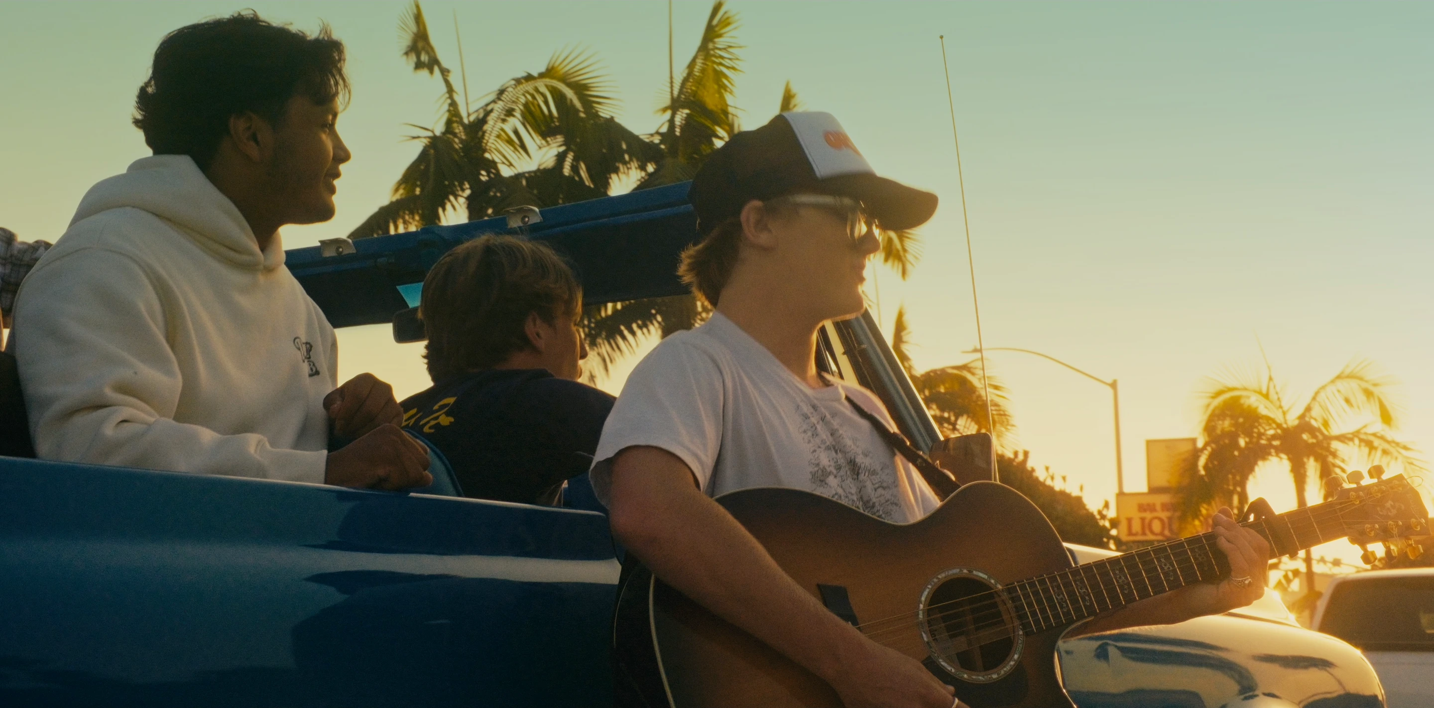 Talan Carthey sings with friends beside a convertible at sunset in Lollygag