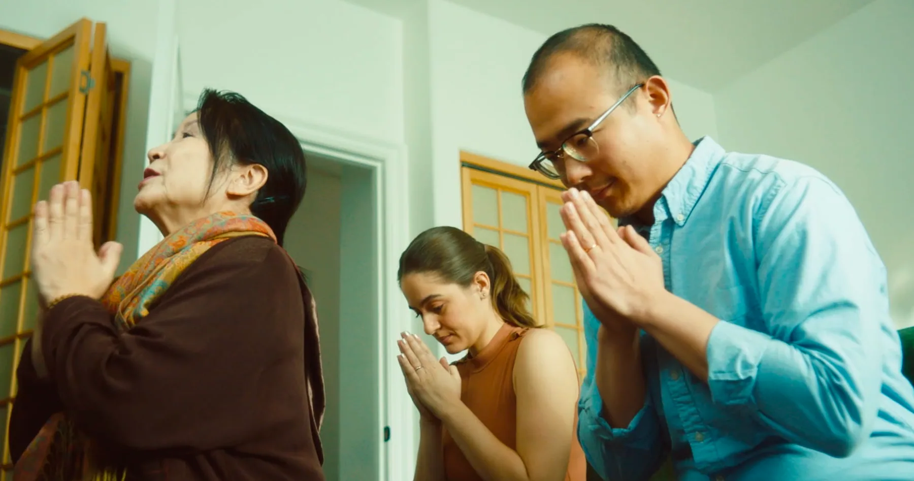 Three family members in a comic prayer gesture