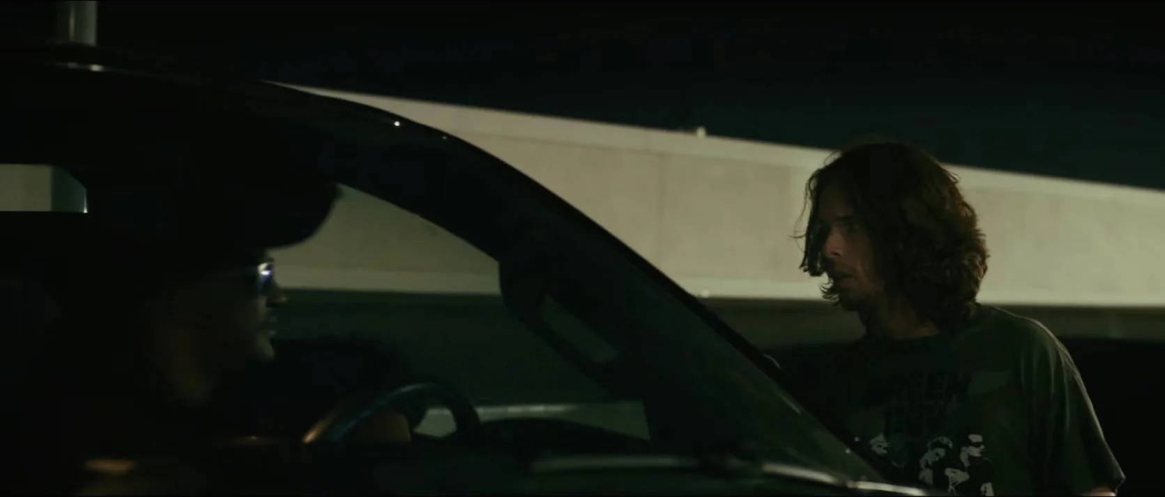 A confrontation beside a car under hard parking-lot light